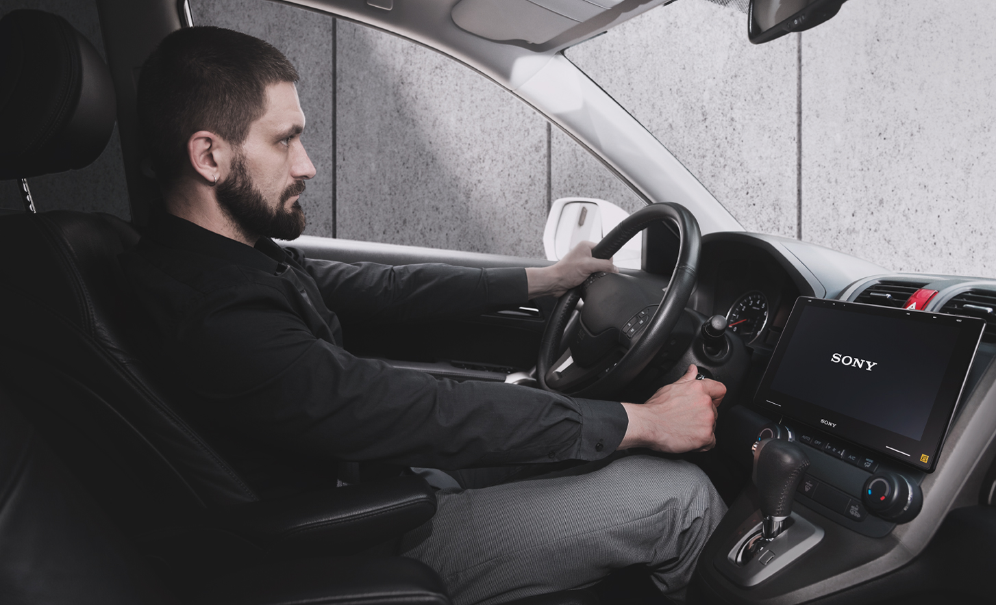 Bild på en person som vrider om tändningsnyckeln med en XAV-9550ES i instrumentpanelen och en Sony-logotyp på skärmen
