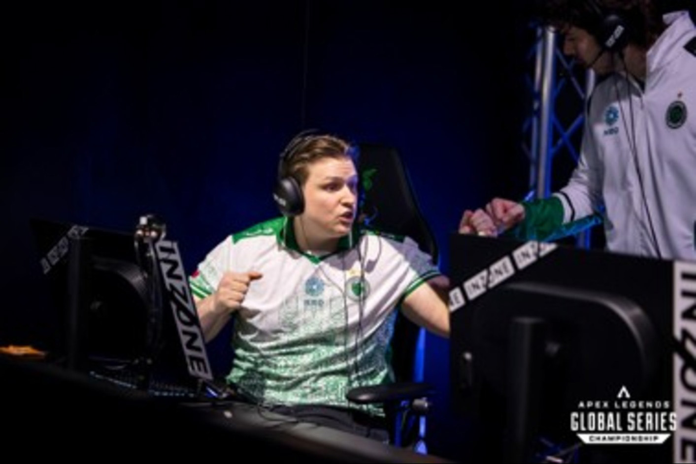 En gamer med INZONE H9 II-spelhörlurar på sig och som pratar med en annan spelare framför en INZONE M10S-spelskärm